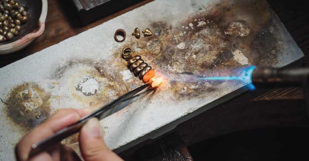 A skilled artisan using a blowtorch and pliers to craft handmade jewelry with precision.